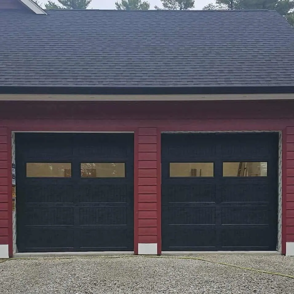 Two black doors on a red barn-style garage