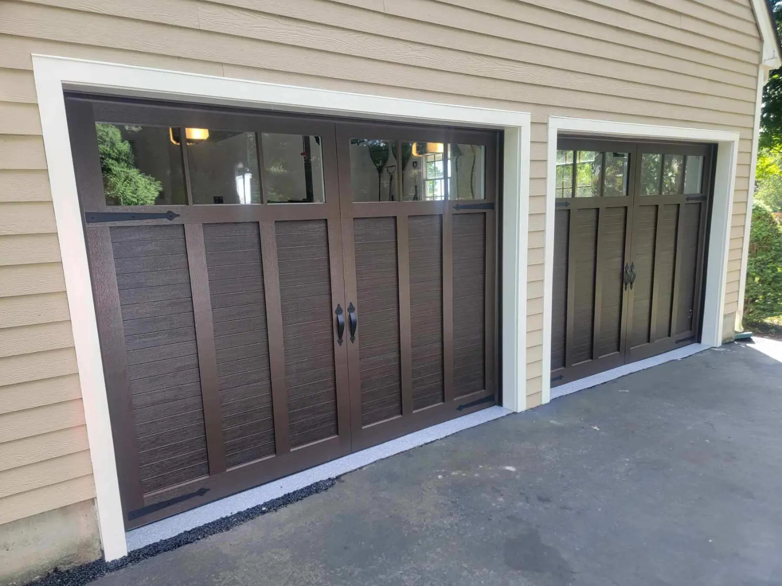 A brown wood-look carriage door on a beige house