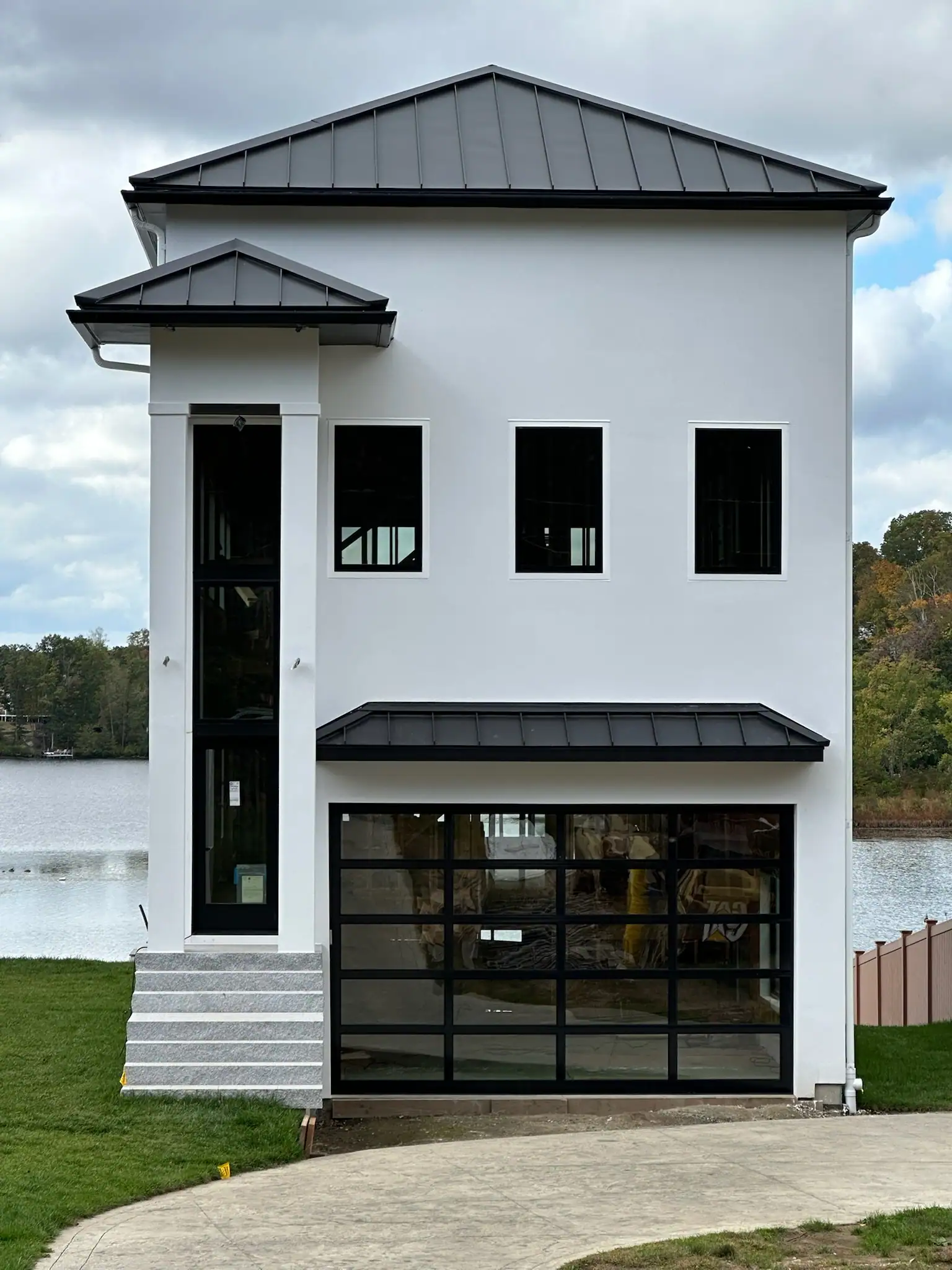 A full-view glass garage door on a modern lakeside home