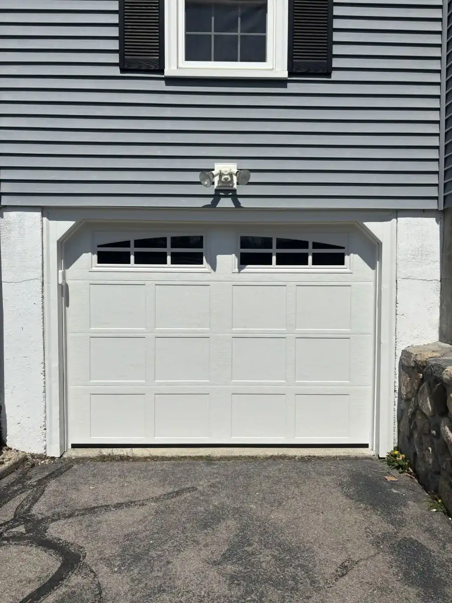 A white carriage-style door with a stone-front garage